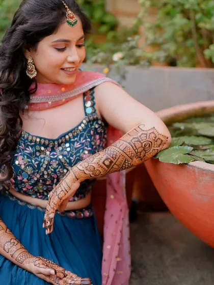 A client posing by a lotus pond, her beautiful mehndi complementing the serene setting.