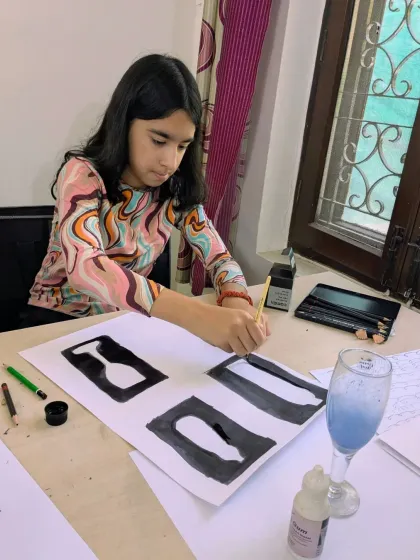 A student deeply focused on her negative space painting exercise. This technique helps artists see shapes more clearly and improves composition skills.
