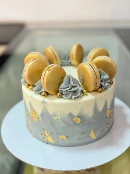 An elegant grey and gold macaron cake, with gold leaf details adding a touch of luxury.