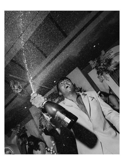 A champagne spray to celebrate the night. This dynamic black and white shot freezes a moment of explosive joy and celebration during the reception.