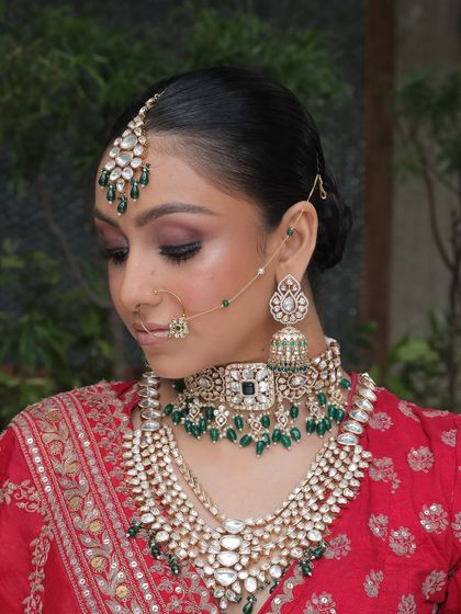 A side profile of the bride, showing how the nath, maang tikka, and layered necklaces come together.