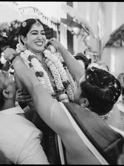 A moment of pure joy as the bride is lifted up during the ceremony. The black and white processing highlights her ecstatic expression and the energy of the celebration.