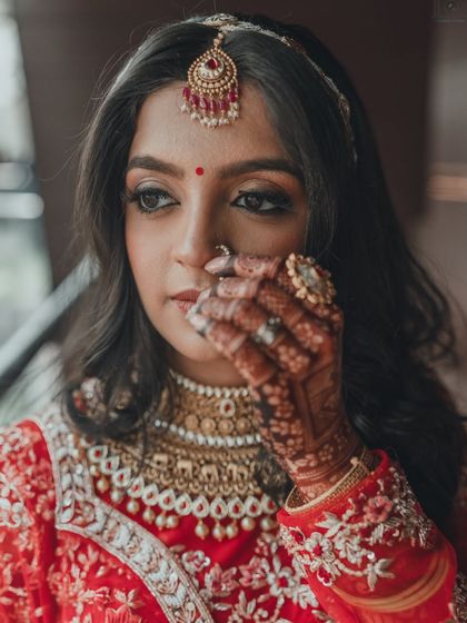 A close-up portrait capturing the bride's stunning makeup, jewelry, and the intricate mehendi on her hands. Every detail is part of her story.