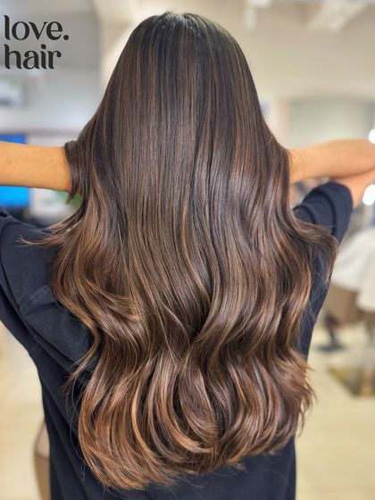 Golden brown texture that looks like sunshine. We gave this client long, flowing layers and a beautiful balayage that mixes warm gold and rich brown for a radiant effect.