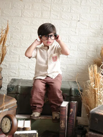 The young boy adjusts his prop glasses, a small, character-filled moment from his vintage-themed shoot.