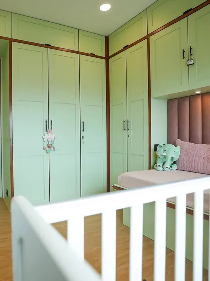 This view shows the full wall of storage in the nursery, painted in a soothing green, providing ample space for clothes and toys.