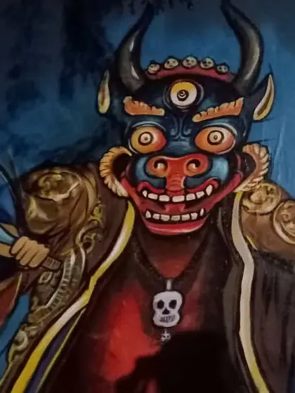 A painting of a three-eyed deity mask with horns and a skull necklace. This piece captures the formidable and protective energy associated with such figures in traditional lore.
