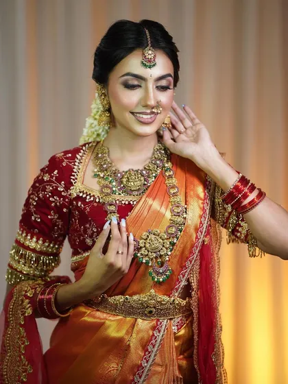 This is my signature South Indian bridal look. The rich, warm tones of this Kanjivaram-style silk saree paired with a deep red velvet blouse create an evergreen elegance that is perfect for your muhurtham.