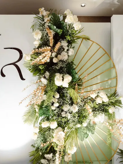 A detailed look at a custom floral backdrop. The couple's monogram is seamlessly integrated into the design, which features lush white flowers and unique fan-shaped accents.