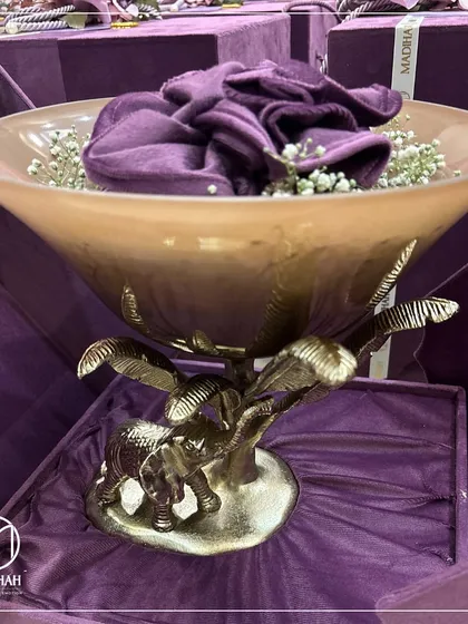 A close-up of the Elephant Bowl, highlighting the warm beige tone of the glass and the detailed craftsmanship of the metal base. This piece is designed to be both a functional bowl and a work of art.