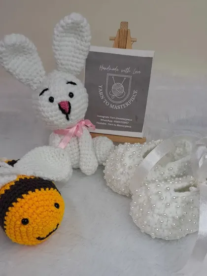 This custom gift hamper was created for a baby girl, featuring a bunny doll, a bee toy, and a pair of my classic white pearl booties.