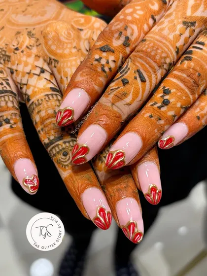 Bridal beauty that perfectly complements traditional henna. This design features a sheer pink base with romantic red heart-shaped tips outlined in gold, blending tradition with modern nail art.
