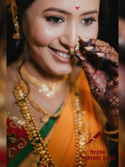 A beautiful portrait of a bride, with her henna-adorned hand delicately touching her nose ring. The mehendi is an essential part of her complete bridal look.