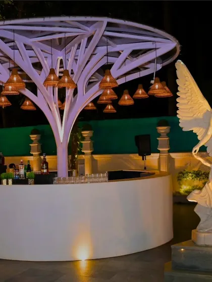 A unique, tree-like bar structure with an angel statue, designed to be a stunning and artistic centerpiece for an outdoor reception.