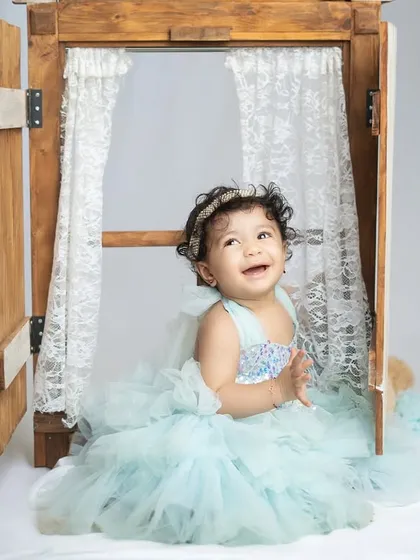 Peeking out from a window prop, this little one's joyful expression is contagious. Props can add a fun, interactive element to milestone shoots.