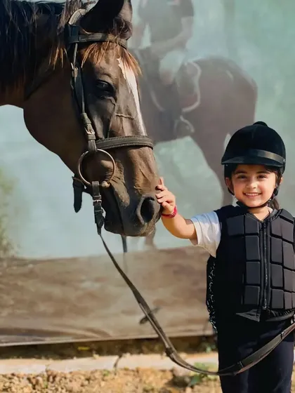 A gentle touch and a happy smile. We encourage children to connect with the horses, fostering a bond of trust and friendship.