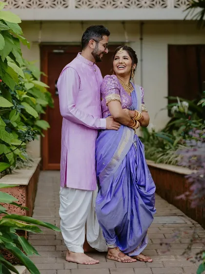 A warm and loving portrait of a Maharashtrian couple, embracing each other with genuine smiles against a backdrop of beautiful greenery.