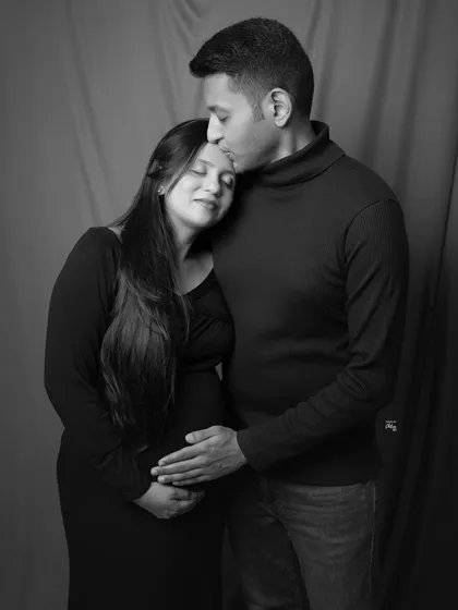 A tender moment of love and protection. This classic black and white portrait captures the quiet promise and gentle connection between the expecting couple.