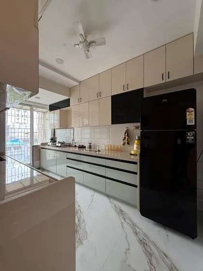 This shot captures the full expanse of the kitchen, including the ceiling fan and overhead cabinet lighting. The large window at the end brings in plenty of natural light.