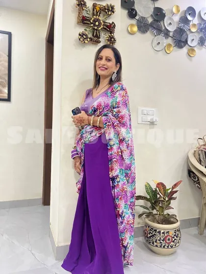 A client looking chic in a purple jumpsuit with a printed floral cape. This is a great example of modern fusion wear.