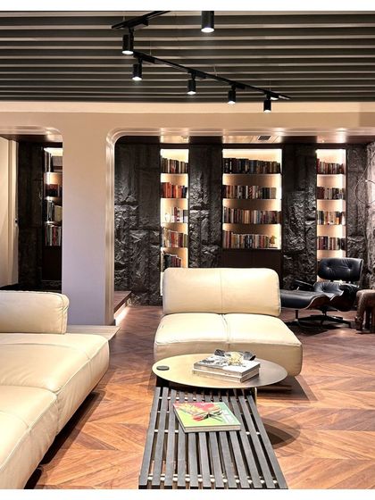 The book nook in the Palm Springs Villa features custom-built shelves integrated into a natural stone wall. The backlighting adds warmth and turns the book collection into a design feature, complemented by a classic lounge chair for comfortable reading.