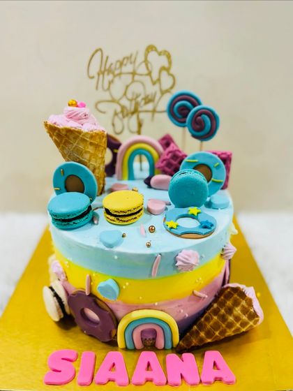 A whimsical and colorful cake loaded with sweet treats. This design features rainbows, ice cream cones, donuts, lollipops, and macarons for a true candyland experience.