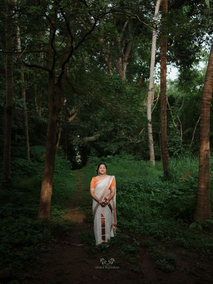 A stunning wide shot of the bride standing alone in a forest, a moment of quiet beauty and anticipation.