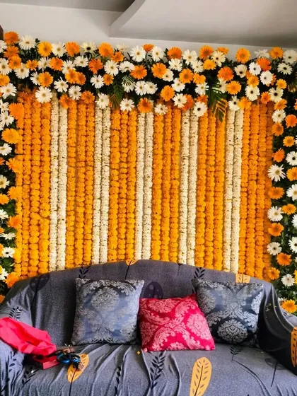 A classic backdrop for a pooja or festival, created with vertical strings of marigolds and tuberoses. The top border of orange and white gerbera daisies adds a finishing touch to this simple and elegant design.