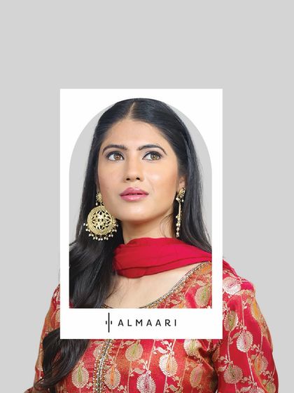 A close-up on a traditional red and gold brocade suit, paired with statement gold jhumkas. This is a classic look that never fails for pujas, family gatherings, or pre-wedding functions.