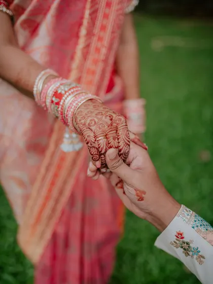 A close-up shot of the couple holding hands after the ring exchange, highlighting the bride's intricate henna and the new rings. This detail shot is a beautiful part of the engagement story.