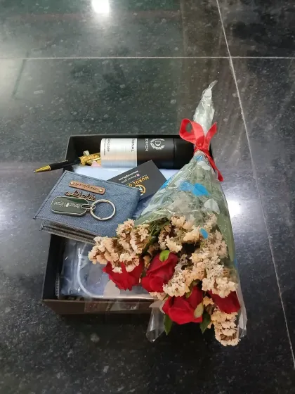 A top-down view of the packed gift hamper, showing the careful arrangement of the personalized accessories, shirt, and flower bouquet.