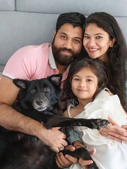 A perfect family portrait with their beloved indie dog, Pakodi. The dog extends a paw as if to join the family pose, creating a unique and memorable shot that showcases their bond.