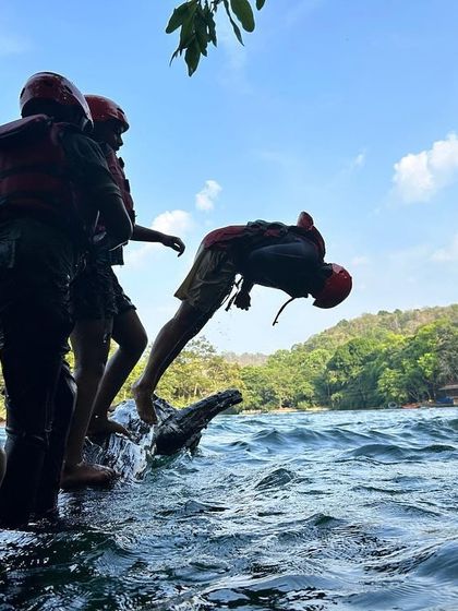 A participant executes a perfect flip into the water from a log, a fun challenge during our river activities.