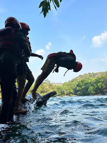 A camper does a flip off a log into the river, a moment of pure adventurous spirit at our Dandeli camp.