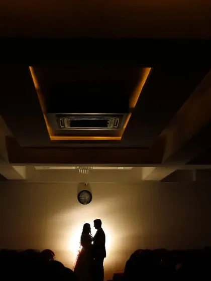 We love creating grand, cinematic moments. By using a single light source to create a silhouette, we turned this couple's portrait into a powerful, movie-like scene, emphasizing their connection against the architectural lines of the hall.