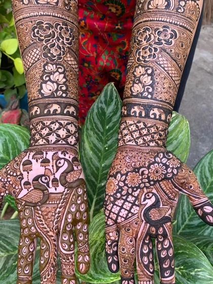 This design is filled with classic bridal elements. You can see graceful peacocks on the palms and tiny elephants marching along the arm bands.