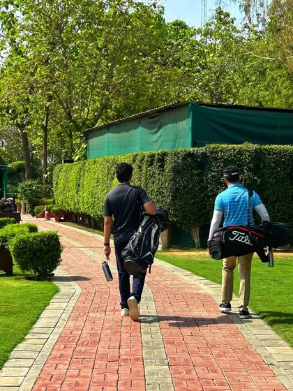 Two golfers with their bags slung over their shoulders, walking down the path ready for a session.