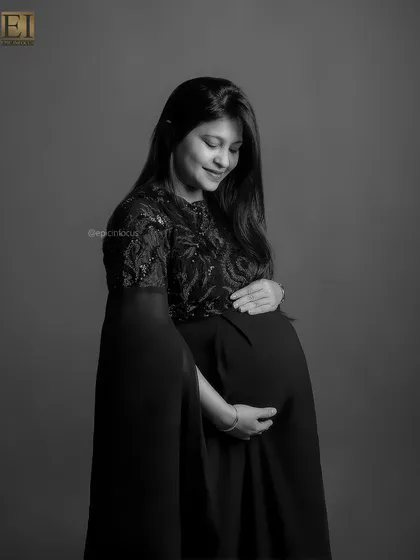 A gentle and introspective black and white portrait of the mom-to-be looking down at her bump.