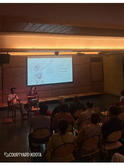 A wider shot of the audience engrossed in the "Lords of Earth and Sea" history talk. The setup is designed to be intimate, fostering a close connection between the speakers and attendees.