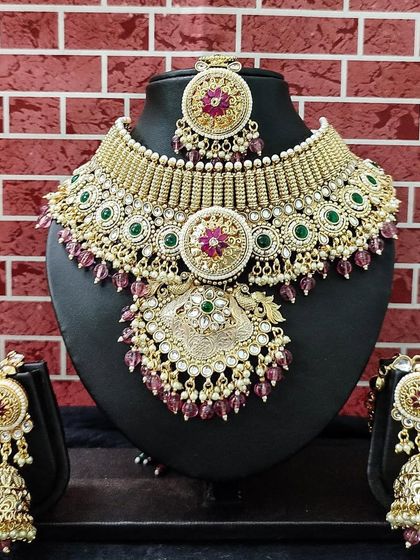 A grand kundan set with a unique design, featuring pink and green stones against a gold base.