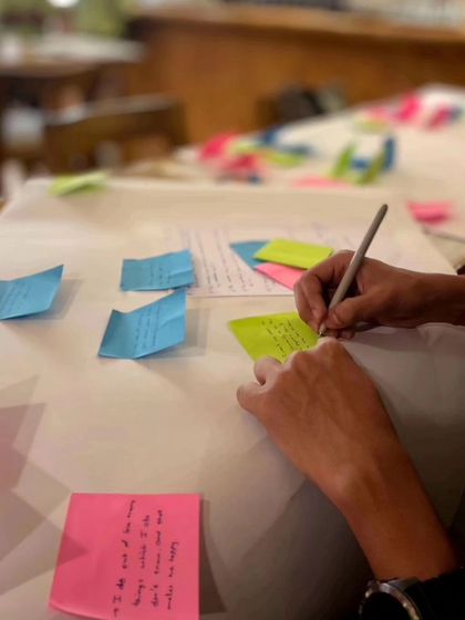 A close-up of a participant working on their happiness design chart, using sticky notes to map out their journey.
