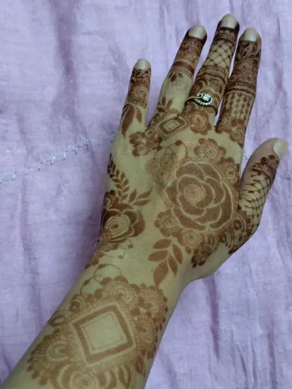 A soft, beautiful floral henna stain. This design covers the back of the hand and wrist with delicate roses and leaves, showing how elegant a mature stain can be.