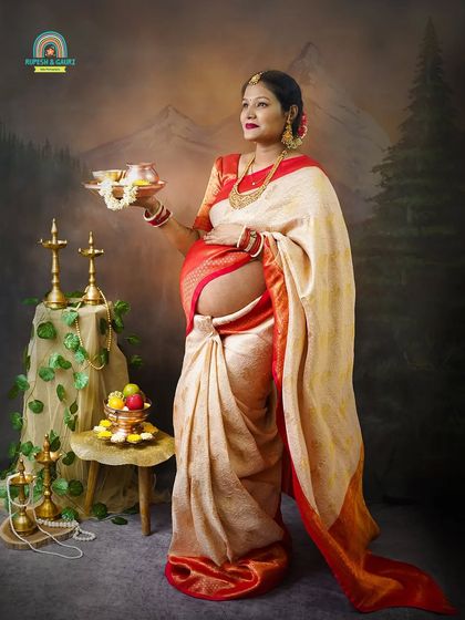 This portrait shows the mom-to-be holding a traditional puja thali, symbolizing blessings for the new life. The bare baby bump is a beautiful and modern touch to the traditional concept.