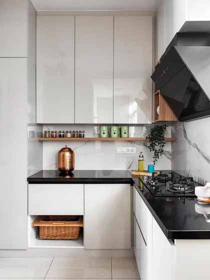 This silver-grey acrylic kitchen maximizes space by extending the wall units up to the ceiling. This approach provides ample storage while creating a sleek, modern look. The black granite countertop and jointless tile backsplash are both durable and budget-friendly.