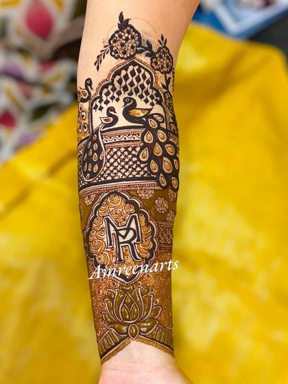 The arm portion of a portrait mehndi, featuring the couple's initials 'MR' and beautiful peacock figures.