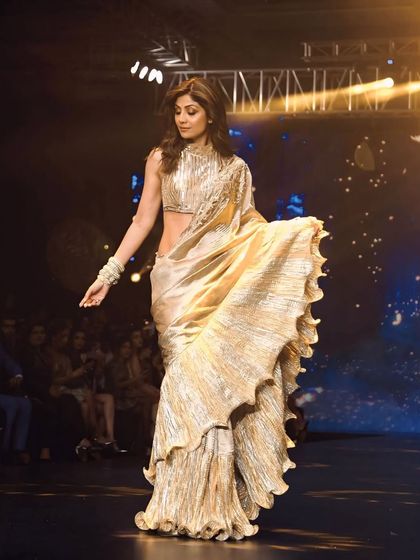 Shilpa Shetty glides down the runway at Bombay Times Fashion Week. This shot captures the movement and shimmer of her golden ruffled saree.
