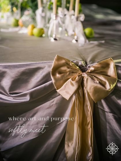 A detail of the table decor with a large gold bow, with the text overlay "where art and purpose softly meet".
