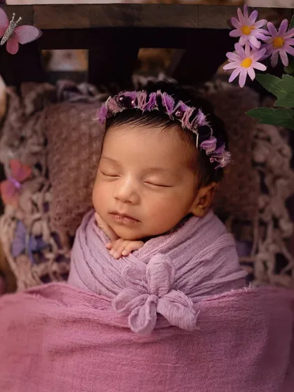 A sleeping newborn in a dreamy, butterfly-themed setup. The soft purple tones and delicate props create a magical and serene portrait.