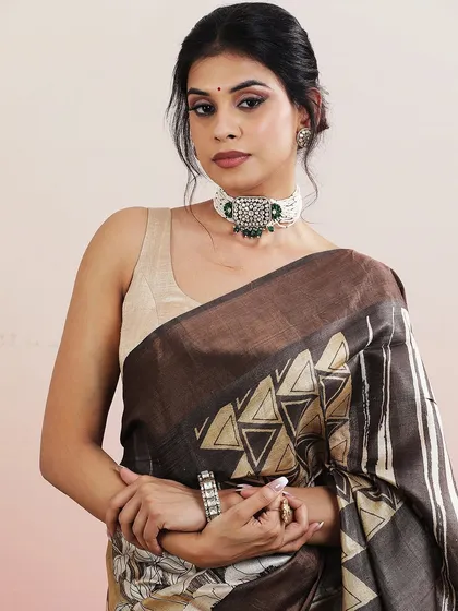A close-up portrait of the model wearing the brown and beige printed saree, paired with a statement choker.