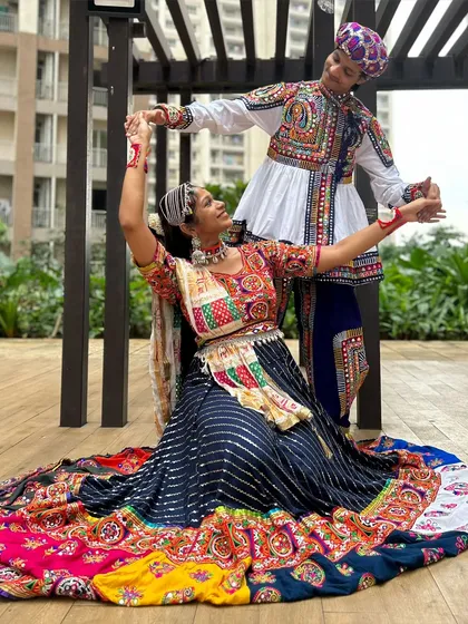 A beautiful dance pose showcasing the full couple's set. The way her lehenga spreads out and his Kedia flares shows these outfits are made for movement.